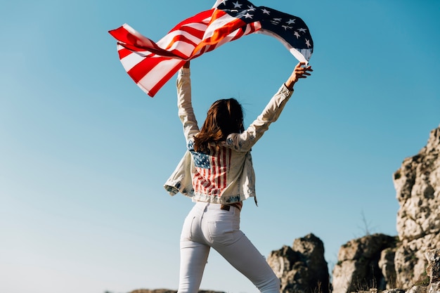 Glückliche Frau, die Hände mit amerikanischer Flagge anhebt