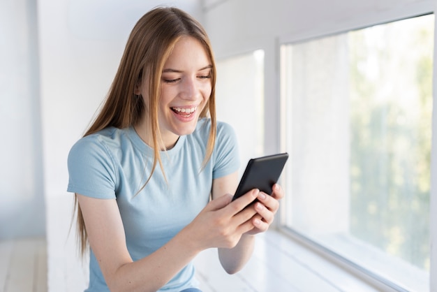 Kostenloses Foto glückliche frau, die ihr telefon überprüft