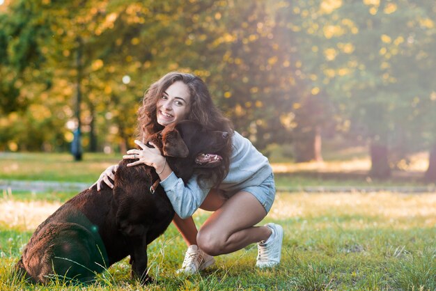 Glückliche Frau, die ihren Hund im Garten liebt