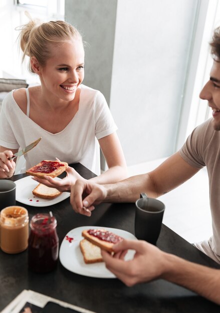 Glückliche Frau, die ihren Mann betrachtet, während sie Frühstück essen