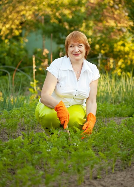 Glückliche Frau, die im Gemüsegarten arbeitet