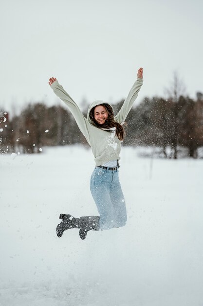 Glückliche Frau, die im Winter draußen springt