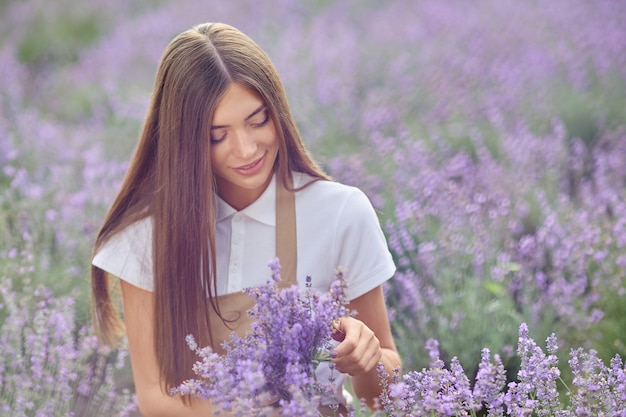 Glückliche Frau, die Lavendelblumen im Feld sammelt