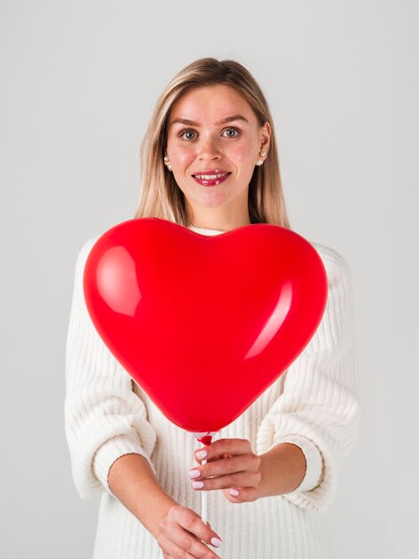 Glückliche Frau, die mit Ballon für Valentinsgrüße aufwirft