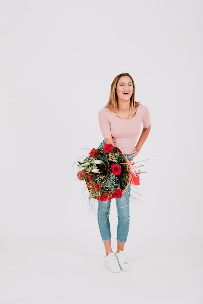 Kostenloses Foto glückliche frau, die mit blumenstrauß von rosen steht