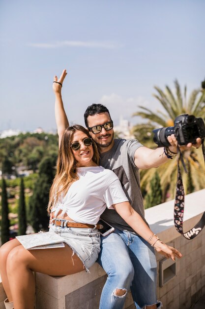 Glückliche Frau, die mit ihrem Freund nimmt selfie auf Bogenkamera sitzt