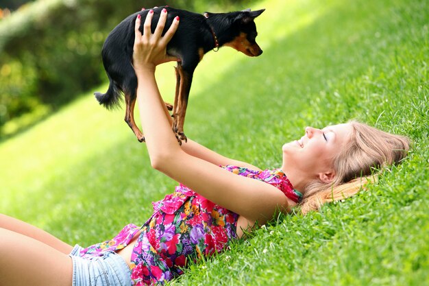 Glückliche Frau, die mit ihrem Hund auf dem Gras liegt