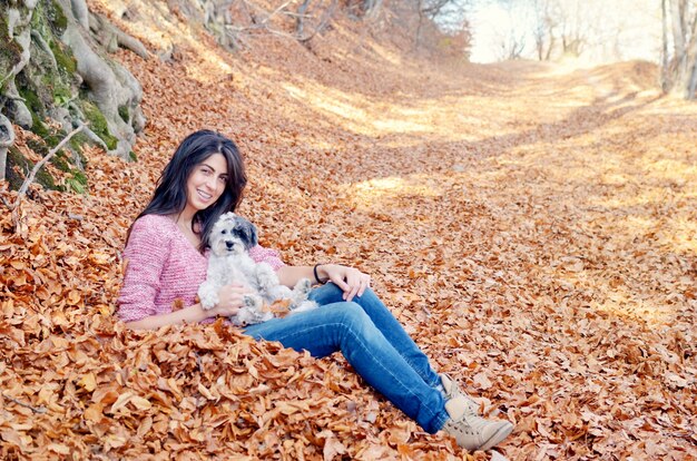 Glückliche Frau, die mit ihrem Hund auf einem Herbsttag