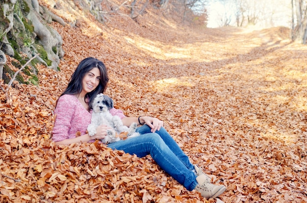 Glückliche Frau, die mit ihrem Hund auf einem Herbsttag