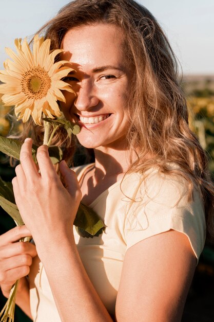 Glückliche Frau, die mit Sonnenblume aufwirft