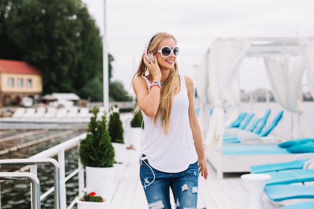 Glückliche frau, die musik auf pier hört