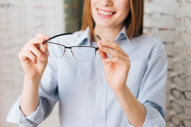 Glückliche Frau, die nach neuen Gläsern am Optometriker sucht