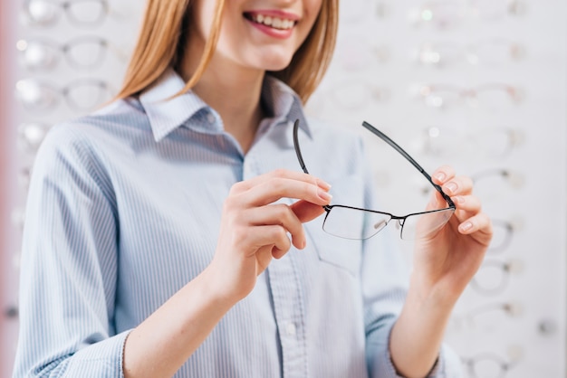 Glückliche Frau, die nach neuen Gläsern am Optometriker sucht