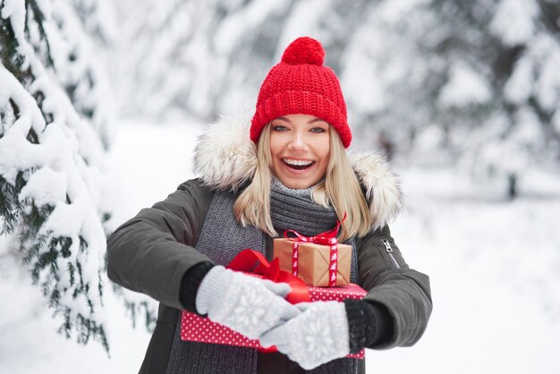 Glückliche Frau, die Stapel von Weihnachtsgeschenken hält