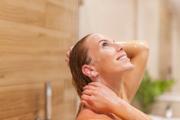 Glückliche Frau, die unter der Dusche entspannt