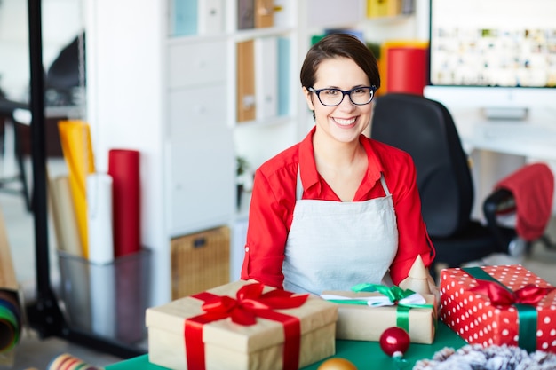 Glückliche Frau, die Weihnachtsgeschenke oder -geschenke verpackt