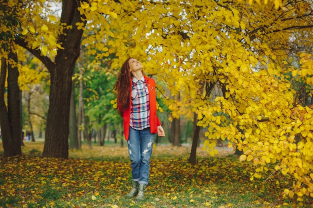 Glückliche Frau, die zu Herbstbäumen aufgeregt schaut