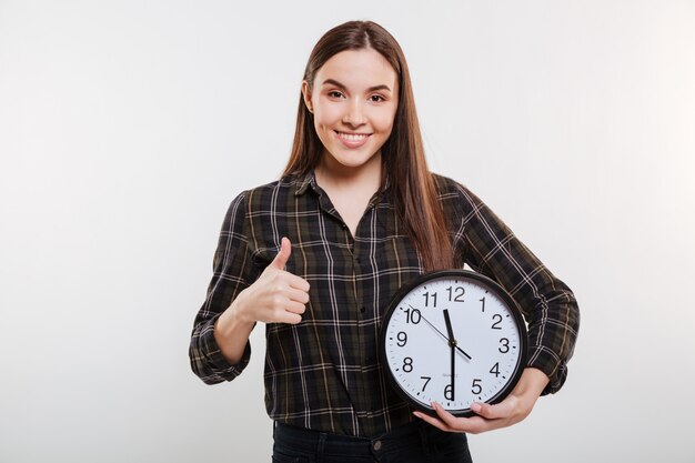 Glückliche Frau im Hemd, das die Uhr hält