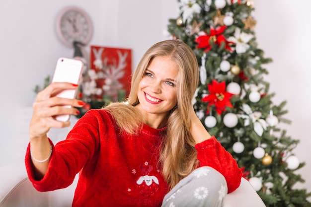 Glückliche Frau in der Strickjacke, die selfie nimmt