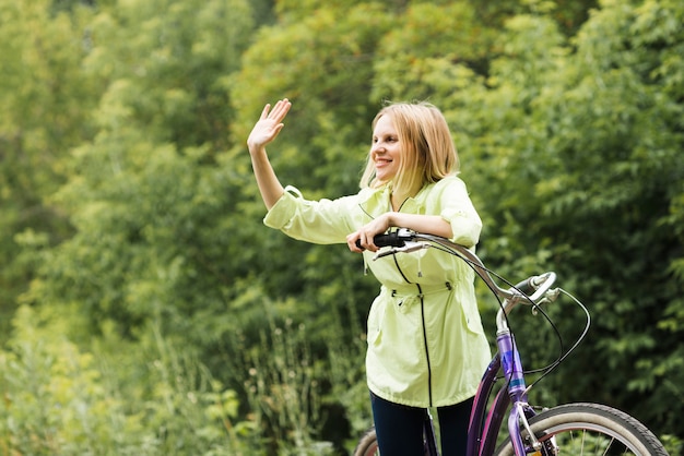 Glückliche Frau mit dem Fahrrad winken