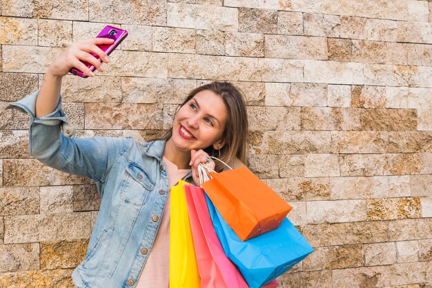 Glückliche Frau mit den Einkaufstaschen, die selfie nehmen