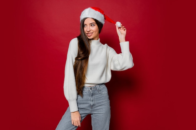 Glückliche Frau mit erstaunlichen langen Haaren in der Weihnachtsmannmütze, die aufwirft