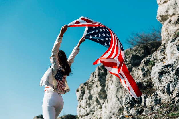 Glückliche Frau mit fliegender amerikanischer Flagge