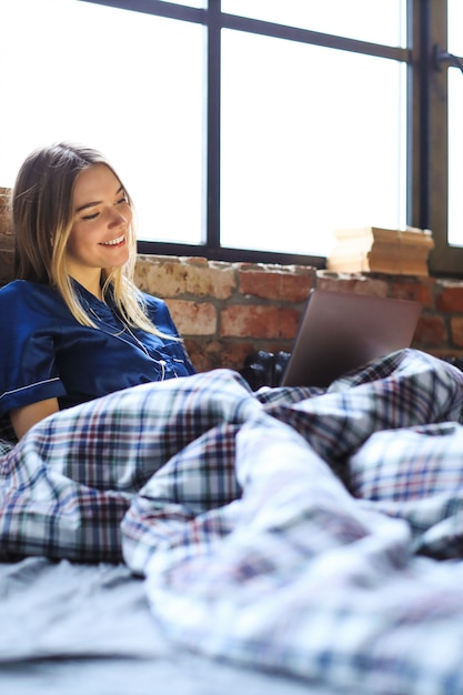 Glückliche frau mit laptop auf bett