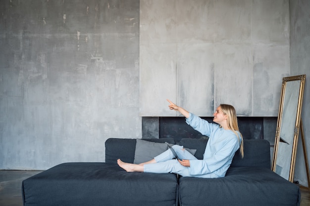 Kostenloses Foto glückliche frau mit silbernem laptop beim sitzen auf dem sofa