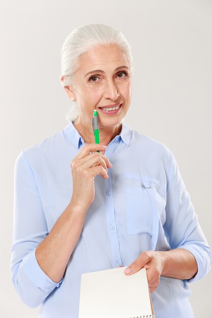 Glückliche Frau mit Stift und Notizbuch suchen und lächeln