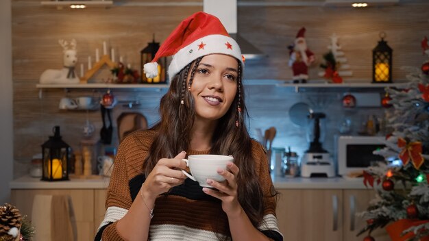 Glückliche Frau mit Weihnachtsmütze, die an die Weihnachtszeit denkt