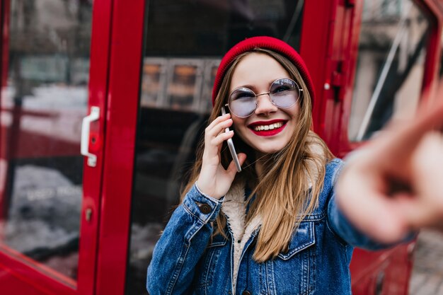 glückliche Frau mit weißer Haut, die am Telefon spricht.