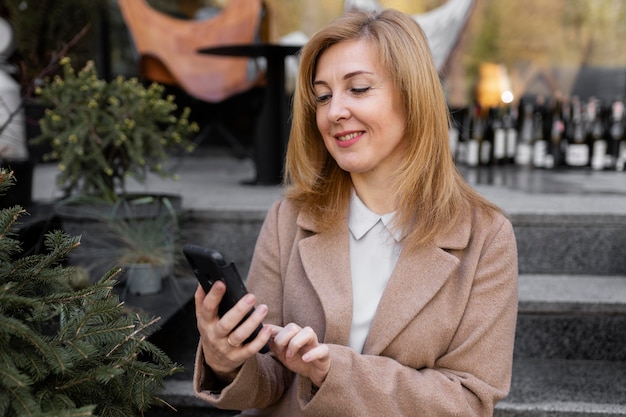 Kostenloses Foto glückliche frau mittleren alters, die ihr telefon überprüft