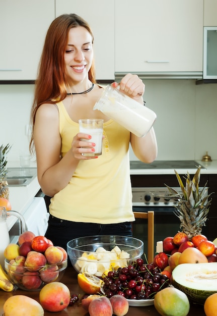 Glückliche Frau trinkt Milch Cocktail mit Früchten