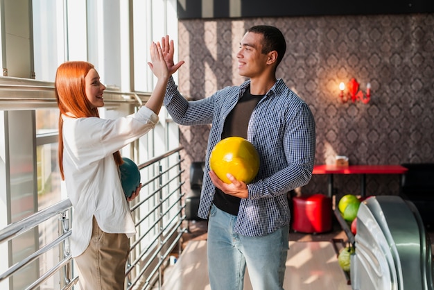 Glückliche Frau und Mann, die bunte Bowlingkugeln hält