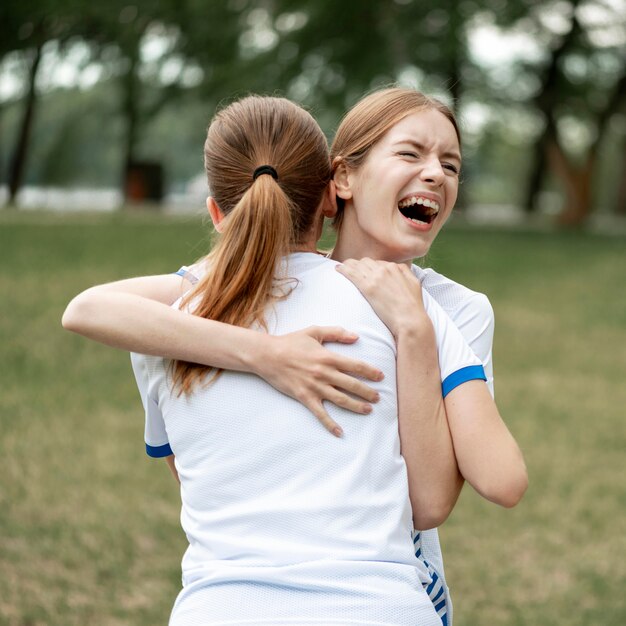 Glückliche Frauen, die auf Fußballfeld umarmen