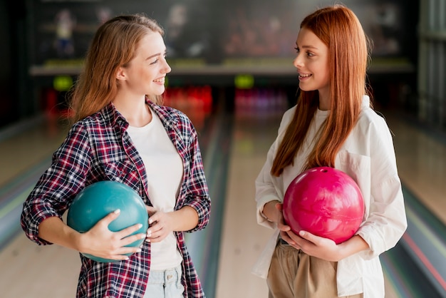 Glückliche Frauen, die in einem Bowlingspielverein aufwerfen