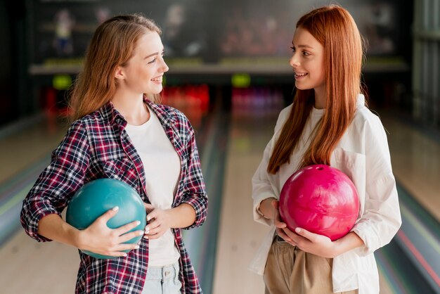 Glückliche Frauen, die in einem Bowlingspielverein aufwerfen