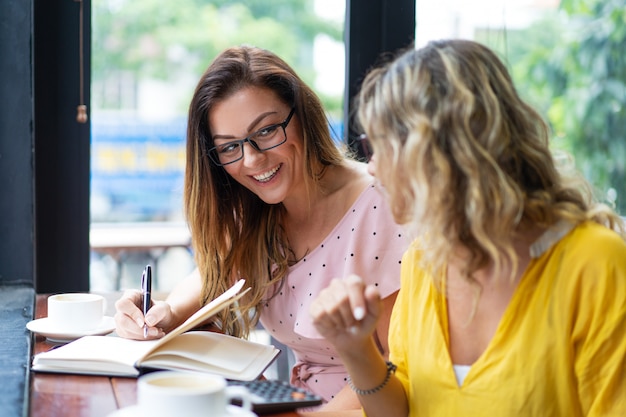 Glückliche Frauen, die Kaffee trinken und im Café arbeiten