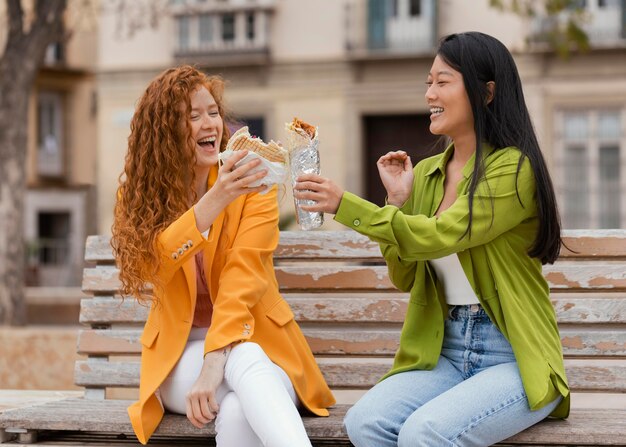 Glückliche Frauen, die zusammen Straßenessen essen