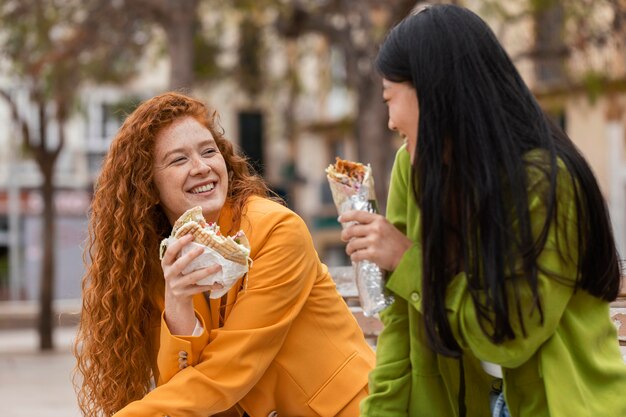 Glückliche Frauen, die zusammen Straßenessen essen