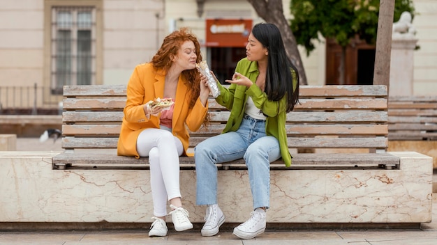 Glückliche Frauen, die zusammen Straßenessen essen