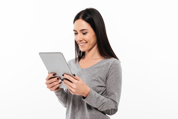 Glückliche Frauenstellung lokalisiert unter Verwendung des Tablet-Computers.