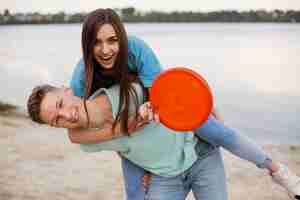 Kostenloses Foto glückliche freunde des mittleren schusses, die mit frisbee herumalbern