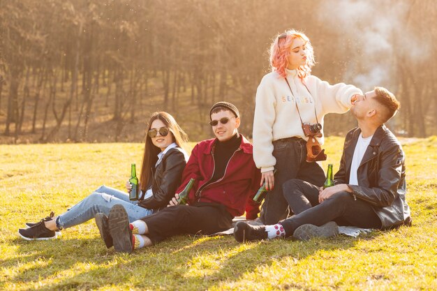 Glückliche Freunde, die auf Gras mit Bier sitzen und Spaß haben