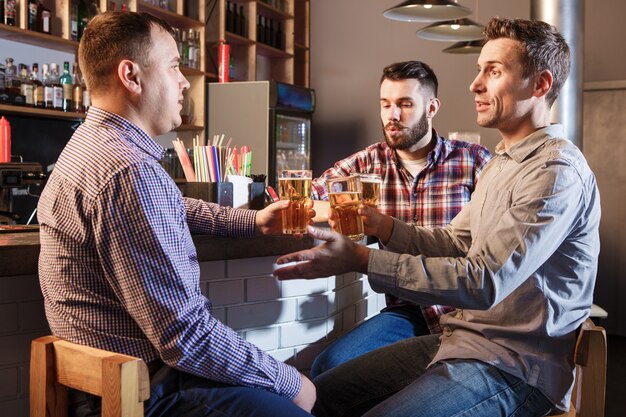 Glückliche Freunde, die Bier am Zähler in der Kneipe trinken