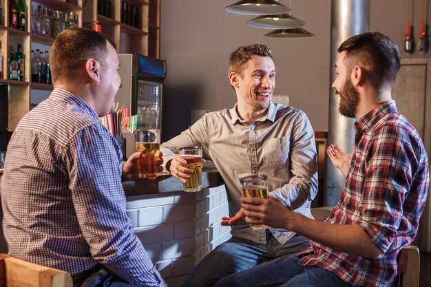 Glückliche Freunde, die Bier am Zähler in der Kneipe trinken