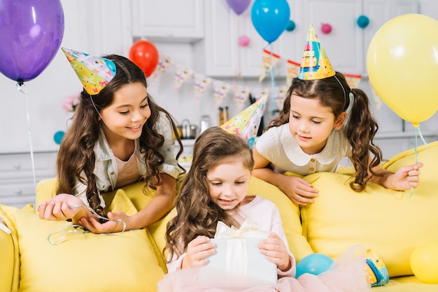Glückliche Freunde, die das Geburtstagsmädchen öffnen das Geschenk zu Hause öffnen