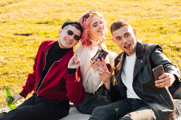 Glückliche Freunde, die das selfie sitzt auf Gras nehmen und Spaß haben