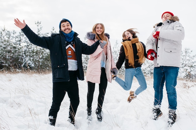 Glückliche Freunde, die in Winterwald springen